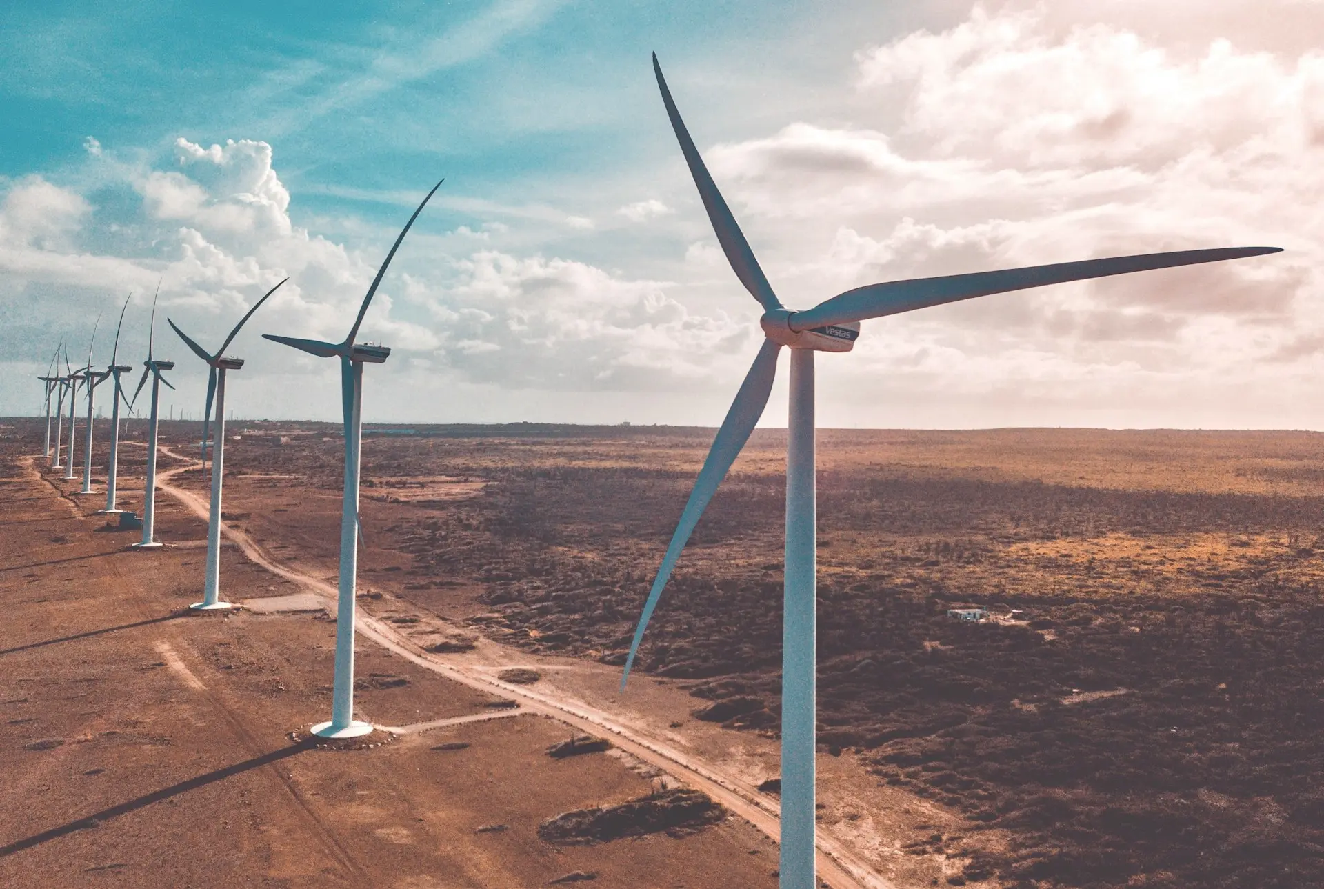 wind turbines on brown sand under white clouds and blue sky during daytime